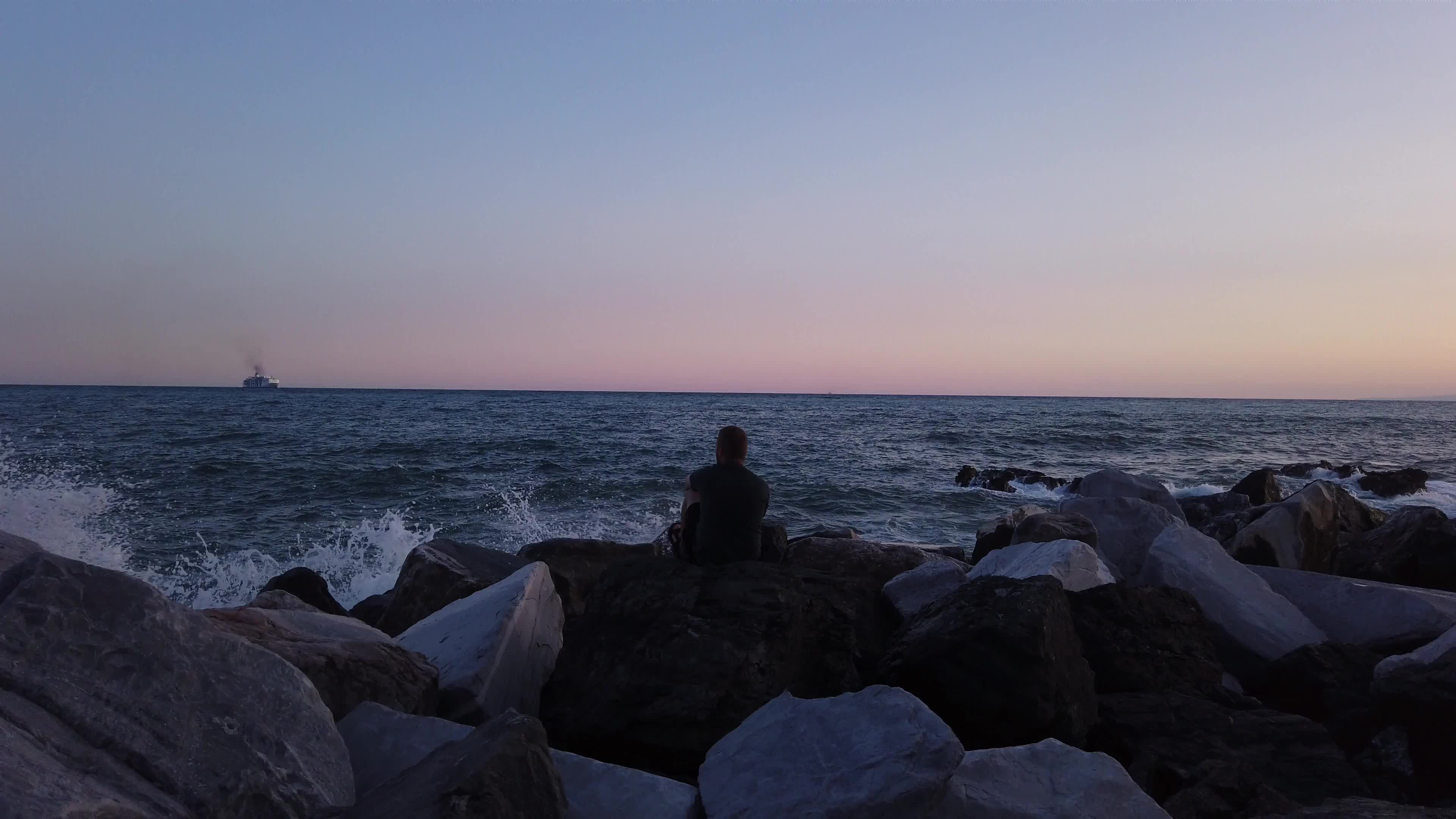 男人坐在海边岩石上看大海